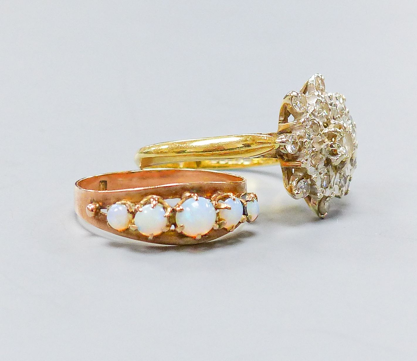 A yellow metal (stamped 9) and graduated five stone white opal set half hoop ring, size M, gross 1.2 grams and and 18ct gold and diamond chip cluster ring, gross 4.6 grams.